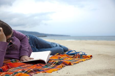 Young Girl reading a book on the Beach.の写真素材