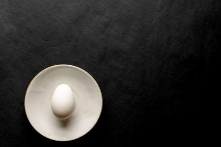 Egg in the white plate with black background and copy space.