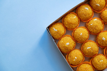 Laddu sweets kept in the box packing with pale blue background and copy space. Laddu or laddoo is spherical Indian sweet made of various ingredients and made during various Indian Hindu festivals.の写真素材