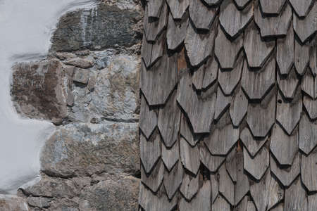 sunburned wooden shingles on a facade next stone wall to use as a backgroundの写真素材