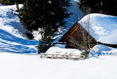 romantic wooden hut in deep snowy winter landscape in Tirol with big snow on the roof of the cabin