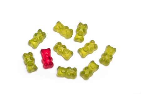 group of green gummy bears in which one red is different as concept for individuality and being different isolated on a white backgroundの写真素材