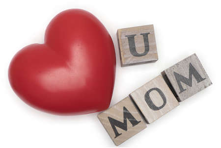 a big red heart next to wooden letter cube showing mom isolated on white background as a concept for...