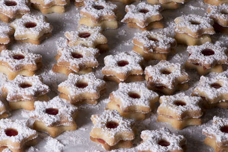 A baking tray full of star-shaped shortbread cookies with jam and powdered sugar Christmas cookiesの写真素材