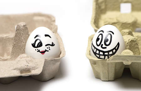 Close up of two eggs with painted faces a woman with a man funny flirting isolated on white...