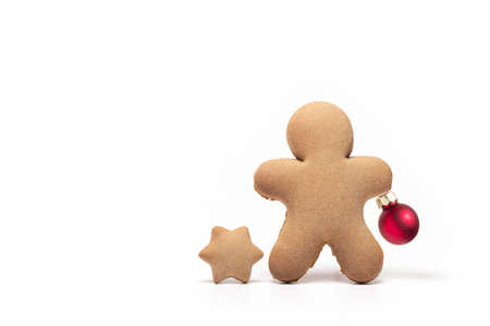 Close up of gingerbread man next to star made of gingerbread holding small red Christmas tree ball...