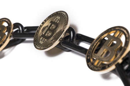 Close up of gold bitcoin coins on black chain isolated on white background as concept for blockchain...