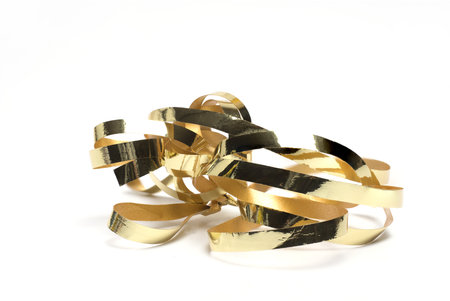 Close up of curly gold gift ribbon on white background as a concept for gift wrapping and presentsの写真素材