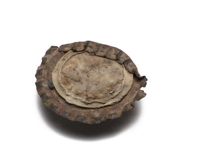 Close up of crown cap seen from below rusty old flattened and dirty on white background
