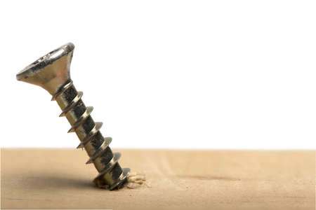 Close up of bronze golden partially screwed in wooden threaded screw in piece of wood on white backgroundの写真素材