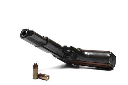Close-up of lying semi-automatic black pistol with two cartridges caliber nine millimeters as ammunition on white backgroundの写真素材