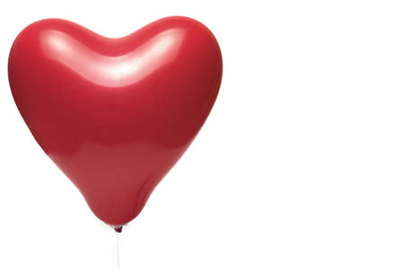 Close up of red balloon filled with air in shape of heart on white background concept for love relationship birthdayの写真素材