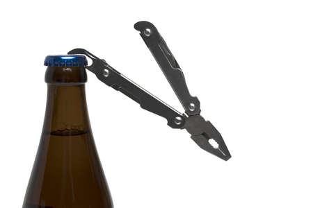 brown beer bottle close up with blue crown cork and bottle opener on pocket knife on white...