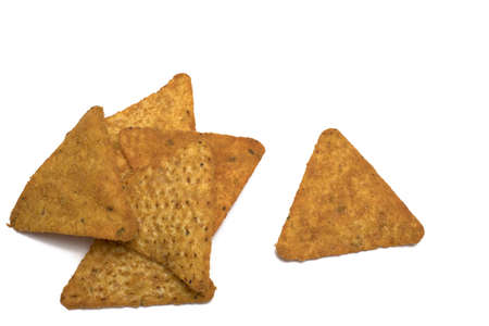 Close up of stack of triangular golden brown crispy fried tortilla chips and single piece next to it on white backgroundの写真素材