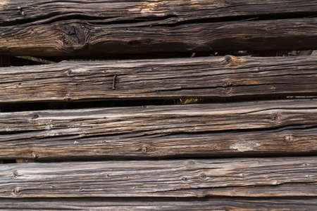 Close-up of old weathered sun burned barn with lying logs as walls and well visible texture of old wood to use as backgroundの写真素材