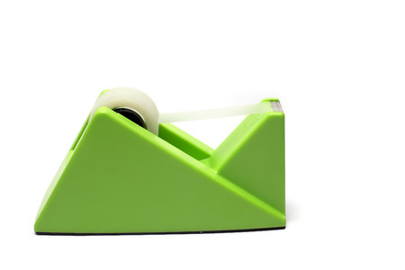 Close up side view of big green solid heavy tape dispenser with transparent plastic strip as office equipment on white backgroundの写真素材