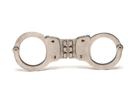 Close up of pair of handcuffs with closed shackles on white background as concept for police arrests and convictionsの写真素材