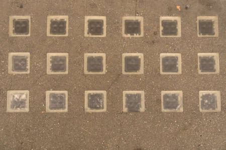 Close up of geometrically laid glass blocks bricks set into sidewalk to illuminate basement space for use as backgroundの写真素材