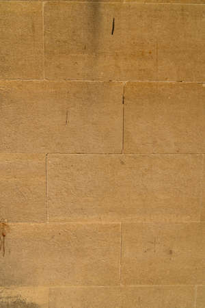 Historical beige yellow sandstone block brick wall close up old facade with rectangular shaped stones for use as backgroundの写真素材