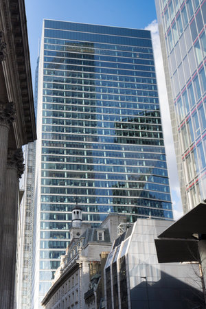 City view in London of glazed towering skyscraper behind historical low buildings as concept for contrast of old and modern architecture against blue skyのeditorial素材
