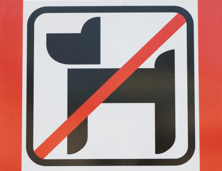 Close-up photo of a sign with a dog crossed out in red announcing a prohibited area for no dogs in a public parkの写真素材