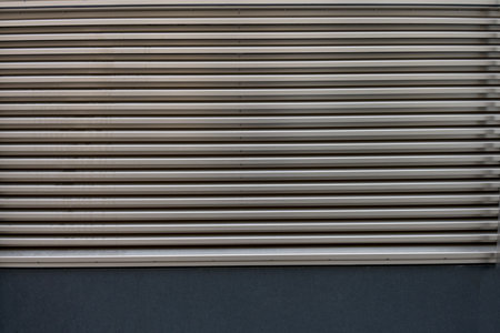 Close up partial view of silver gray metal aluminum ventilation grille with even horizontal divisions to use as backgroundの写真素材