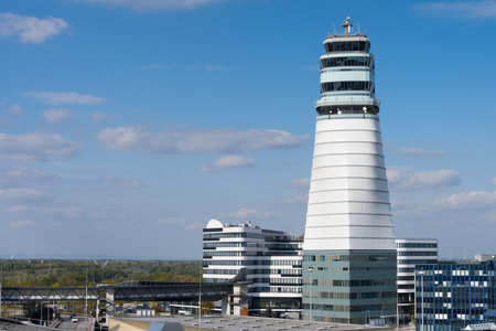 Vienna airport with high tower of air traffic control and various logistics buildings in front of blue skyの写真素材