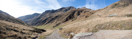 Alpine terrain in East Tyrol Austria with gravel road between mountain ranges against partly cloudy sky as a concept for roads and trails in the mountainsの写真素材
