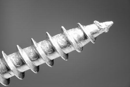 Tip of curved thread of a metal screw as extreme macro close up diagonally in image as concept for threaded screws craft and drillingの写真素材