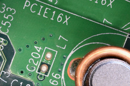 Partial view extreme close up detail of green computer board with frosty brown round component visible solder joints lettering as concept for computer chip pc internet and electronicsの写真素材