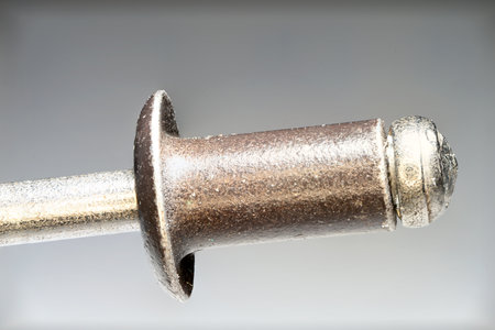 Extreme close up of not yet processed iron steel sheet metal blind rivet with pull pin against gray gradient background as concept for metal rivet craft and sheet metal jointsの写真素材