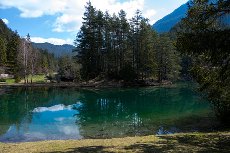 idyllic mountain lake with reflecting surface and crystal clear water surrounded by forest meadows and high mountains and a wooden hut on the lake in Tyrolの写真素材