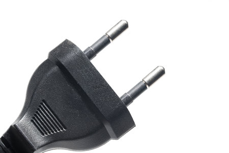 Close up of black 220 volt eu european power plug for powering electrical appliances as concept for alternating current europe on white background with copy spaceの写真素材