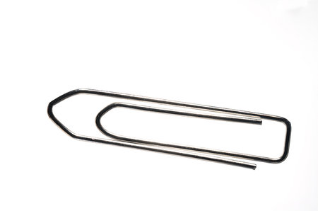 Extreme close up of large silver metal paper clip against white background with copy space as concept for office paperwork and administrationの写真素材