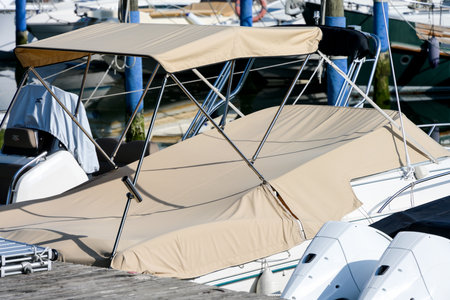 Partial shot close up of beige foldable roof sun shade bikini bimini top sun sail sun canopy and sport boat motor boat covered with brown canvas in a harbor as a concept for protection from sun wind and weatherの写真素材
