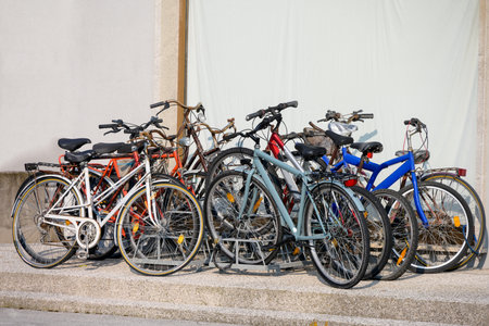 A group of old partly rotten colorful abandoned rusted simple cycles partly locked partly damaged in front of monotonous background as a concept for mobility with single lane vehicles bike paths and bicyclesの写真素材