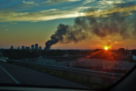 Downtown burning in the evening lots of smoke and a beautiful sunset in the backgroundの写真素材