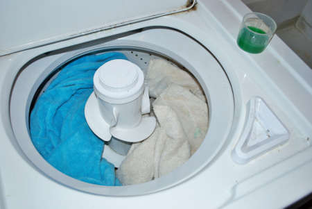 load of dirty towels in a washing machine with laundry detergentの写真素材