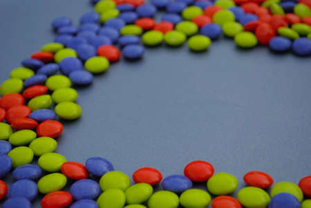 Colorful Halloween candy background orange blue green purple candy coated milk chocolate room for...