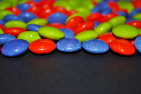 Colorful Halloween candy background orange blue green purple candy coated milk chocolate room for...