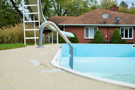 backyard swimming pool with pool slide and ladder emptied out shutting down for winterのeditorial素材