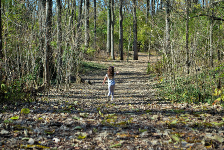 unrecognizable little girl hiking through the woods by herselfの写真素材