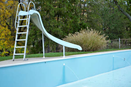 backyard swimming pool with pool slide emptied out shutting down for winter