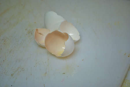 Close up of two cracked eggshells on a well used cutting board