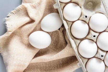 Cardboard egg rack with eggs on gray background. Top view. Rural still life, natural organic healthy...