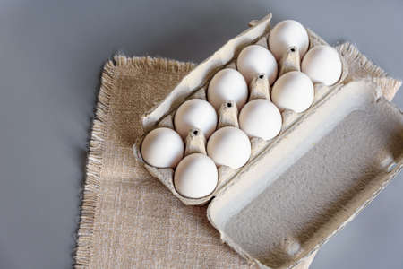 Cardboard egg rack with eggs on gray background. Top view. Rural still life, natural organic healthy food with free spaceの写真素材