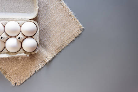 Cardboard egg rack with eggs on gray background. Top view. Rural still life, natural organic healthy food with free spaceの写真素材