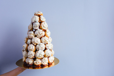 Crockenbush or Profiterole tower (cone of glazed profitroles) on blue background with free space. Selective focusの写真素材