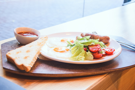 Fried eggs with appetizing sausages, toast bread and fresh salad.の写真素材