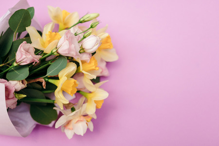 A bouquet of daffodils and eustoma on a pink background with an empty space for advertising or text. Top viewの写真素材